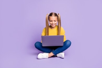 full length photo of positive interested kid sit legs crossed folded work her laptop read social media news wear casual style clothing isolated over violet color background