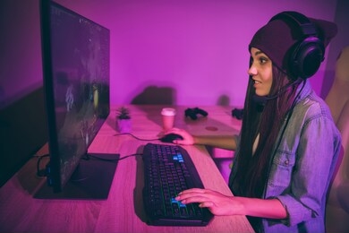 side profile photo view of young millennial gamer expressing astonishment violet purple on face pressing keyboard in pink lights at night