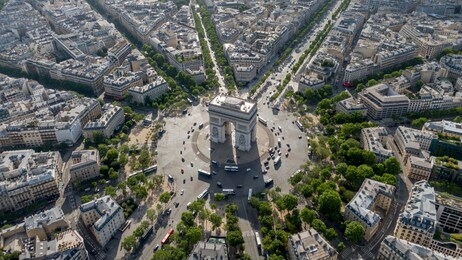 aerial photo of the arc de trioumphe in paris, france. photo taken early morning, champs elysees leads from the arc to the top right corner of the photo. 