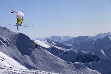 freestyle ski jumper with crossed skis in snowy mountains