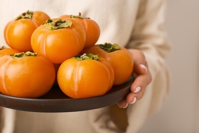 woman holding plate with ripe persimmons, closeup