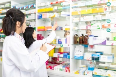 two asian pharmacist check and assess  drugstore, unity and teamwork, happiness organization, they holding assessment form and write report, they reading prescription and manage drug in store