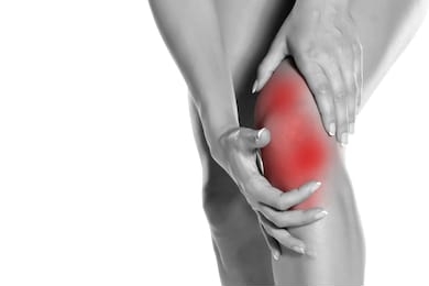 woman holding her painful knee on white background