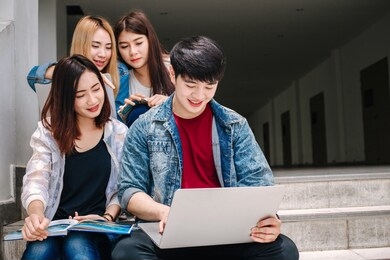 university life. friends preparing for classes, sitting in university campus with books and devices