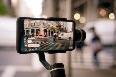 man using phone with stabilizer and taking pictures and live video in new york city. vlog, video blogging, street photography concept. 