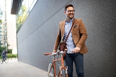 happy young stylish businessman going to work by bike