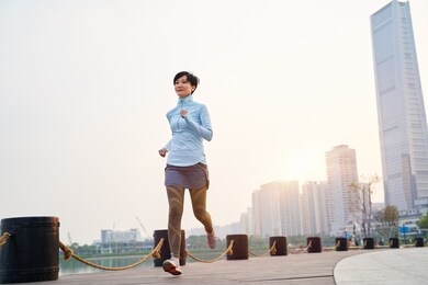 portrait of asian beauty jogging in city park at sunset