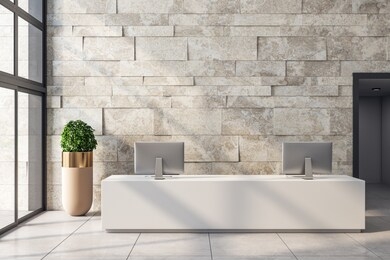modern office lobby interior with reception desk, computers, shadows, city view, daylight and empty copyspace on stone wall. mock up, 3d rendering 