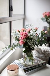 mini rose and mini carnations bouquet with gypsophila in glass vase over white coffee table