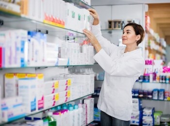 positive female pharmacist suggesting useful body care products in pharmacy