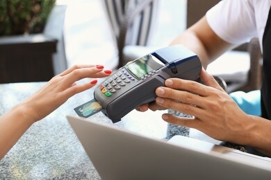young woman paying by credit card in cafe, closeup