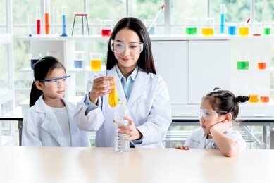 asian female teacher scientific experiments are being performed for children students using balloons and water bottles, which are experiments about water pressure, to education concept.