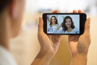 closeup of a female hand holding a cell phone during a skype video call with her friend 