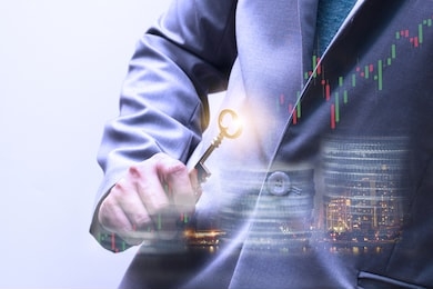 double exposure of tower building , coins and hand’s of businessman holding the golden key. same as the success factor to investment concept. mentor or advisor in financial investment.
