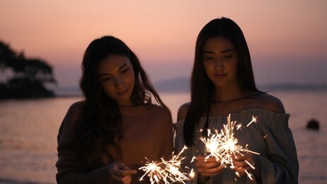 the girl is happily playing with fireworks on the beach.
