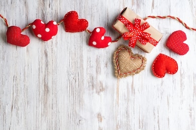 flat lay cute composition with handmade fabric red hearts. gift box with ribbon bow on wooden table. happy birthday or anniversary congratulation. romantic message template with copy space.