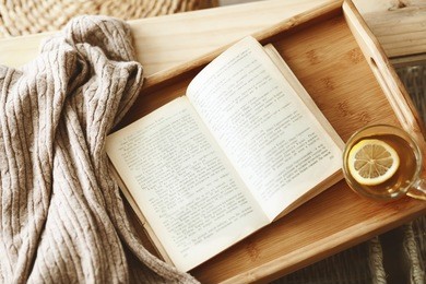 warm knitted sweater and a book on a wooden tray