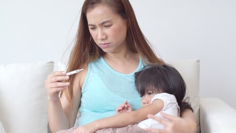 medium shot with young mother check up and treatment her daughter, mother is measure the temperature of little girl and feel anxious about fever