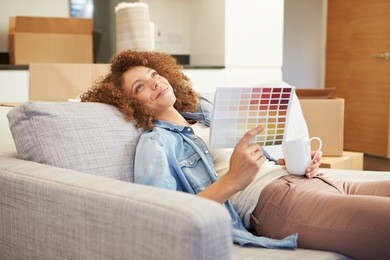 woman sitting on sofa looking at paint charts