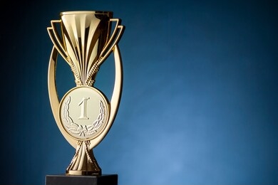 gold championship winners trophy or cup placed to the side on a blue background with copy space