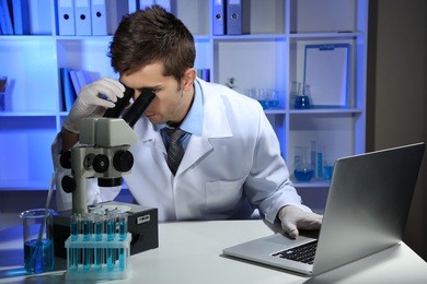 young laboratory scientist  looking at microscope in lab 