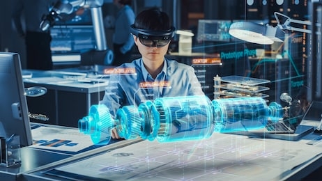 industrial factory chief engineer wearing ar headset designs a prototype of an electric motor on the holographic projection blueprint. futuristic virtual design of mixed technology application.