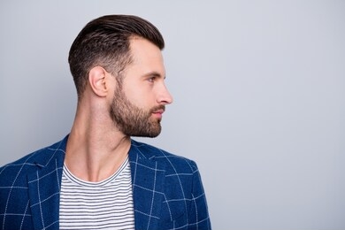 photo of man looking into empty space showing the result of his hairstylist work with bristle on face turning head side profile isolated grey color background
