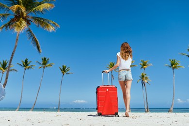 woman with red suitcase beach tropics travel destination