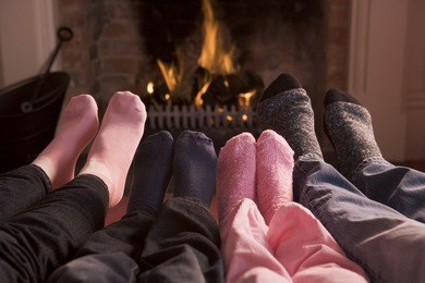 family of feet warming at a fireplace