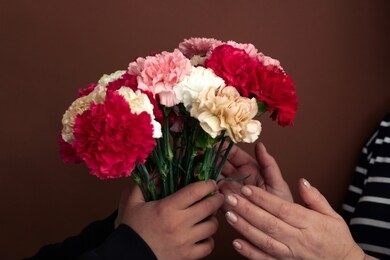woman gives a bouquet of carnations to another woman, close  up female hands with a bouquet of carnations selective focus 