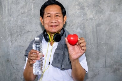 senior asian man smiling in sportswear holding red heart.good life.