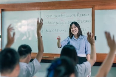 an asian female teacher is teaching japanese. the meaning of texts are "mr. suriya bought a shirt for the teacher, mr ittithep taught me japanese, i have been taught japanese from mr athithep".