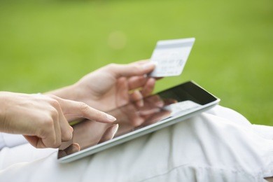 close-up woman's hands holding a credit card and using tablet pc, online shopping, outdoor