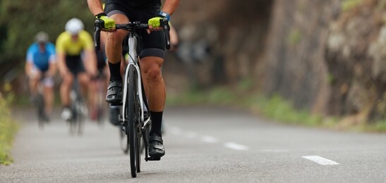 cycling competition,cyclist athletes riding a race,climbing up a hill on a bicycle