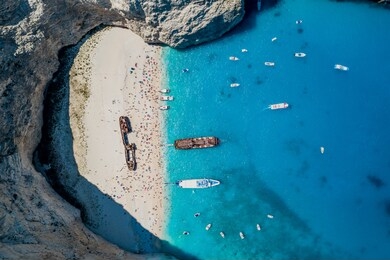 aerial overhead drone shot of zakynthos navagio beach with tourists ,cruise ship and yachts