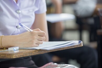 high school,university student study.hands holding pencil writing paper answer sheet.sitting lecture chair taking final exam attending in examination classroom.concept scholarship for education abroad