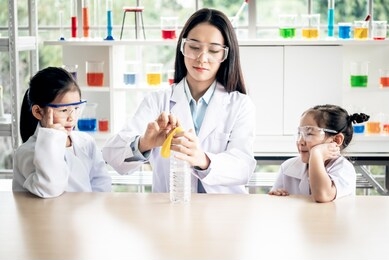 asian female teacher scientific experiments are being performed for children students using balloons and water bottles, which are experiments about water pressure, to education concept.