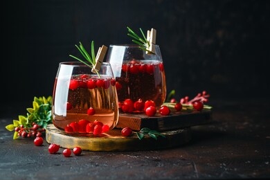 cranberry cocktail with rosemary in two glasses on dark background. copy space