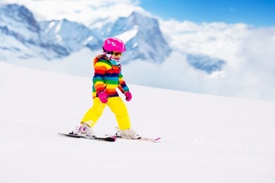 child skiing in mountains. active toddler kid with safety helmet, goggles and poles. ski race for young children. winter sport for family. kids ski lesson in alpine school. little skier racing in snow