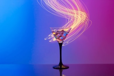 martini cocktail with ice in neon pink and blue light on mirror bar with shining lines. night club, party, cocktail concept. close-up, copy space