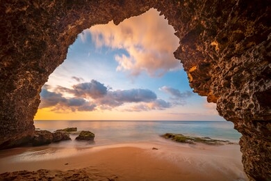 view from the cave a sandy beach along the ocean at golden sunset. bali, indonesia.