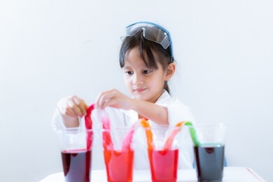 a 4 years old asian little girl is learning about color changing walking water experimental, concept of kid education for fundamental science learning activity.
