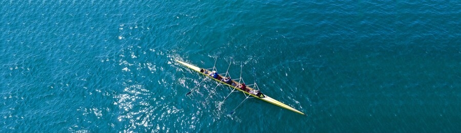 aerial drone top down ultra wide panoramic view of sport canoe rowing synchronous athletes competing in tropical exotic lake