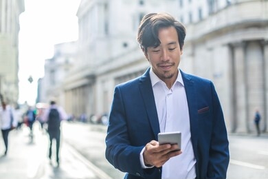 handsome businessman walking in the street, using his phone
