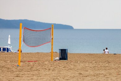 empty volleyball net on a sandy beach on the sea shore in summer.