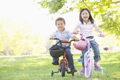 brother and sister outdoors on bicycles smiling