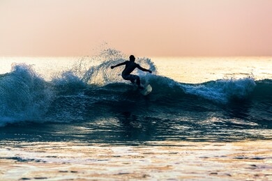  silhouette man playing with surfboard in sea