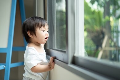 asian cute baby standing and playing a small toy sitting alone on floor at home. the kid holding the toy and question about how to play it. play and learn of young child education concept