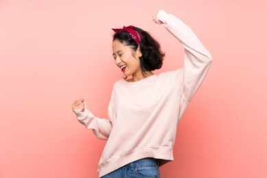 asian young woman over isolated pink background celebrating a victory