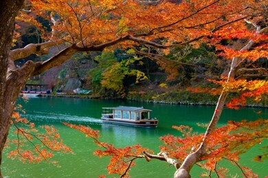 boatman punting the boat at river. arashiyama in autumn season along the river in kyoto, japan.